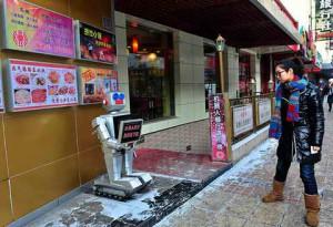 A robot greets people outside a Restaurant
